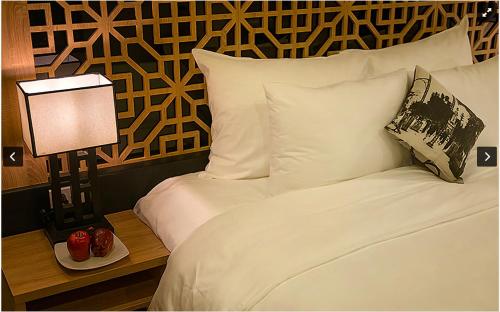 a bedroom with a bed with white sheets and a lamp at Gemini Saigon LUXURY in Ho Chi Minh City