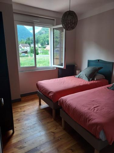 a bedroom with two beds and a large window at le gite du Montcalm in Auzat