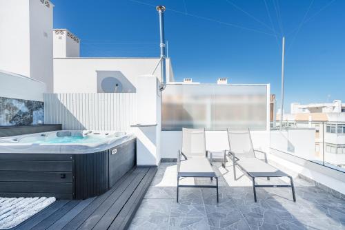 La salle de bains est pourvue d'une baignoire et de chaises sur le balcon. dans l'établissement New Luxury Penthouse beachfront in the Algarve, à Armação de Pêra