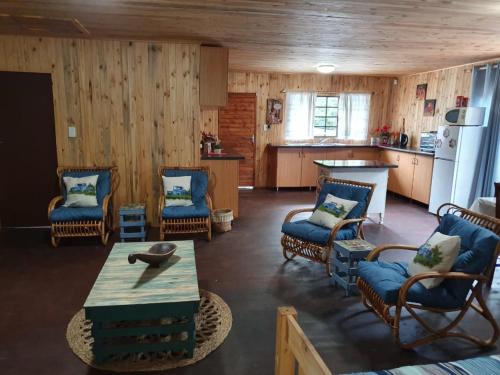 ein Wohnzimmer mit Stühlen und einem Tisch sowie eine Küche in der Unterkunft Hout Huisie in Marloth Park