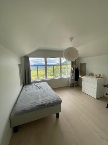 1 dormitorio con cama y ventana grande en Modern cottage, en Sogndal