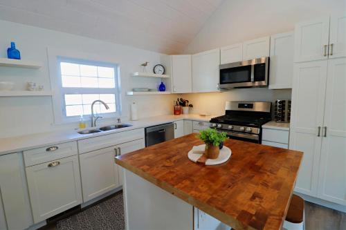 a kitchen with white cabinets and a wooden table at Sandpiper Cottage home in Ashville