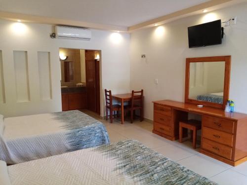 1 dormitorio con 2 camas, escritorio y espejo en Hotel Santa Engracia en Ciudad Valles
