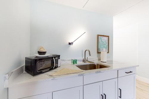 a kitchen counter with a microwave and a sink at Capri 104 in Marco Island