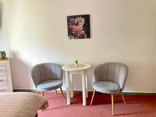 two chairs and a table in a room with a bed at Penzion Moravia - free parking in the city center in Mikulov