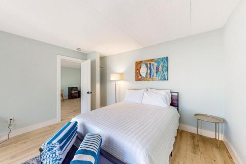 a white bedroom with a bed and a chair at Capri 102 in Marco Island