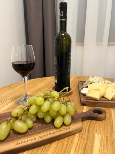 a glass of wine and a bunch of grapes on a table at Jahorina Apartment4Two in Jahorina