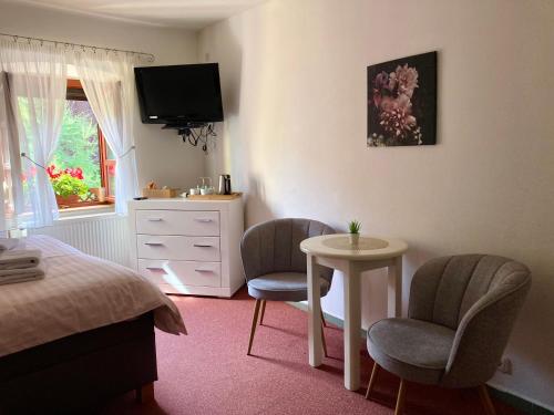 a bedroom with two chairs and a table and a tv at Guesthouse Mikuláš Mikulov - free parking in the city center in Mikulov