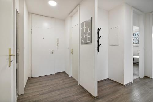 an empty hallway with white walls and wood floors at Wuppertal Stay- Fitter Apartment in Wuppertal