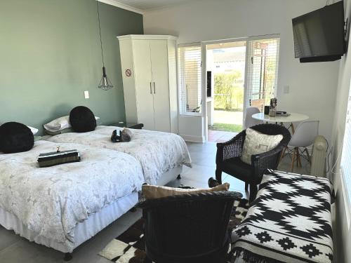 a bedroom with two beds and a chair and a table at Sea-esta in Plettenberg Bay