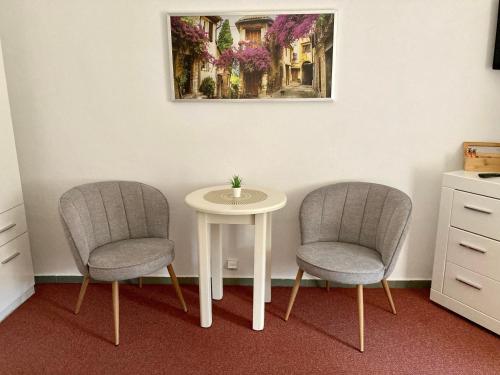 two chairs and a table in a room with a picture at Penzion Moravia - free parking in the city center in Mikulov