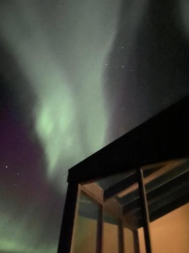 a view of the northern lights from a building with a window at Glass roof lodge with private hot tub in Reykholt