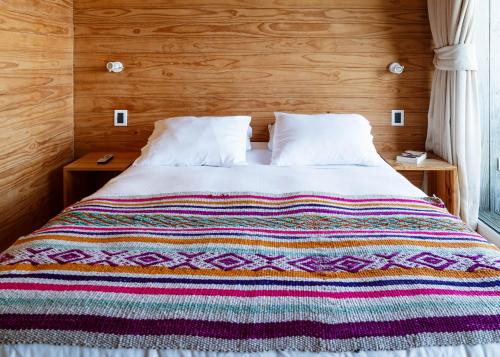 a bed with a colorful blanket on top of it at Lodge del Mar in Pichilemu