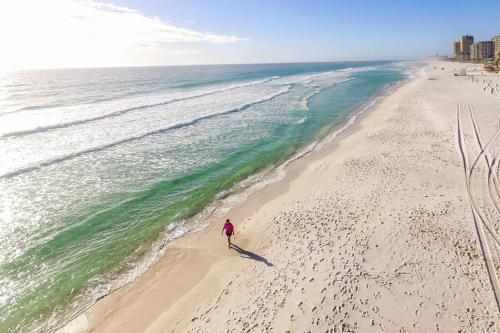 a person walking on a beach near the ocean at SpringHill Suites by Marriott Panama City Beach Beachfront in Panama City Beach