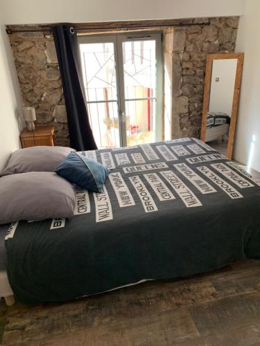 a large bed in a bedroom with a stone wall at La Grange in Avallon