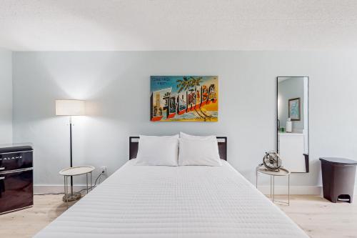a white bedroom with a large bed and two chairs at Capri 107 in Marco Island