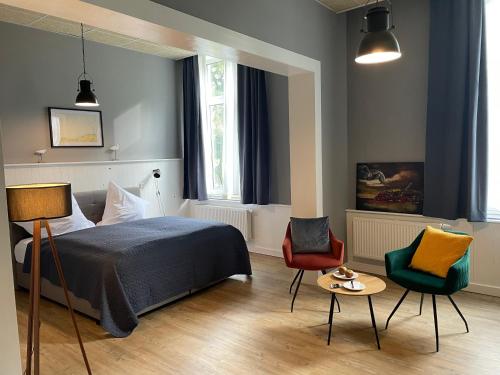 1 dormitorio con 1 cama, 2 sillas y mesa en Hotel Alte Navigationsschule, en Rhauderfehn
