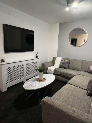 sala de estar con sofá y TV de pantalla plana en Harborne House en Birmingham