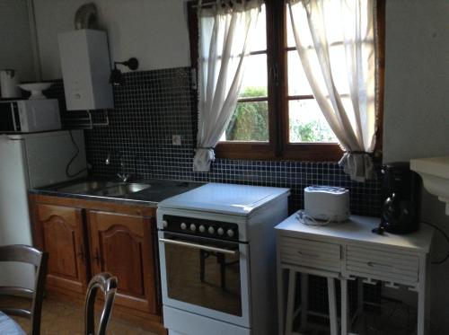 a kitchen with a stove and a window at La Maison d'Ambre in Saint-Laurent-en-Gâtines