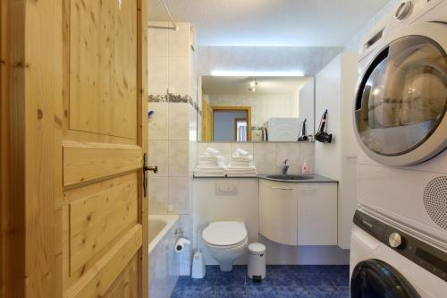 a bathroom with a toilet and a sink and a washing machine at Ferienlenk Mountain Village in Lenk