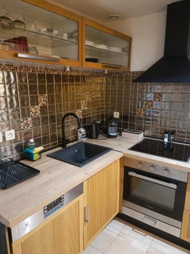 une cuisine avec un évier et une cuisinière dans l'établissement La perle rare Chambly, Proche Parc Astérix , château de Chantilly, à Chambly