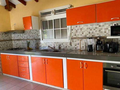 a kitchen with orange cabinets and a counter top at Maison élégante au Moule avec terrasse ensoleillée in Le Moule