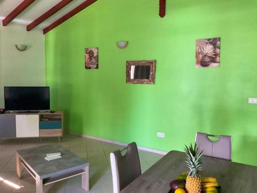 un salon avec un mur vert et une table dans l'établissement Maison de 3 chambres avec terrasse amenagee et wifi a Le Moule, à Le Moule