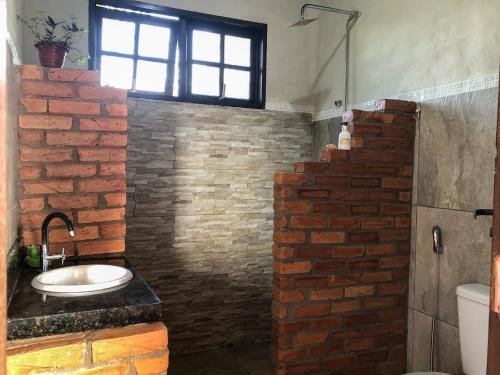 ein Badezimmer mit Waschbecken und einer Ziegelwand in der Unterkunft Espaço Ajna in Alto Paraíso de Goiás