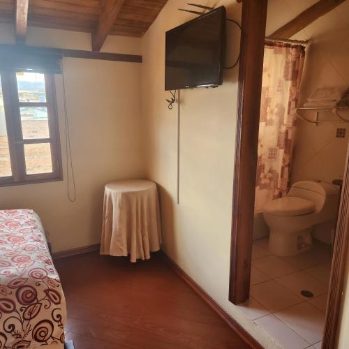 a bathroom with a toilet and a television in it at Hotel Bella Casona in Riobamba