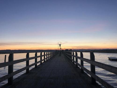 a wooden pier with the sunset in the background at Hotel Wittelsbacher Hof in Utting am Ammersee