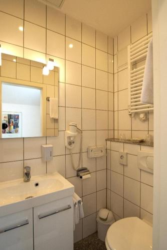 a bathroom with a sink and a toilet and a mirror at Hotel Wittelsbacher Hof in Utting am Ammersee
