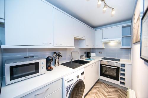 una cucina con armadietti bianchi e lavastoviglie di Very Central Ground floor 2 bedroom apartment a York