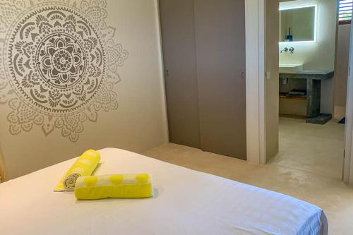 a bedroom with a bed with yellow pillows and a sink at Isla penthouse & garden apartments Bonaire in Kralendijk