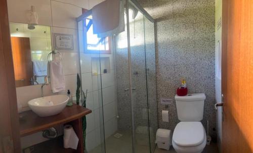 a bathroom with a shower and a toilet and a sink at Residencial Vila Suel in Praia do Rosa