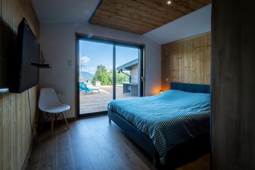 sypialnia z łóżkiem i przesuwnymi szklanymi drzwiami w obiekcie Chalet Luxe et Nature w mieście Anould