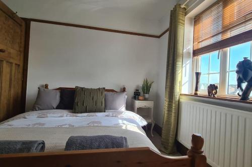 a bedroom with a bed and a large window at House on Costal Village in Peacehaven