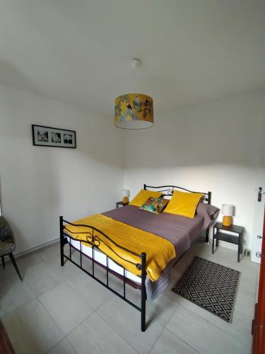 une chambre avec un lit avec une couverture jaune dans l'établissement LE CITRONNIER, à Lamalou-les-Bains