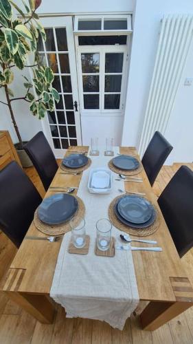 a wooden table with blue plates on it with chairs at House on Costal Village free parking in Peacehaven