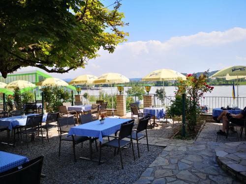 a patio with tables and chairs with a view of the water at Donau-Rad-Hotel Wachauerhof in Marbach an der Donau