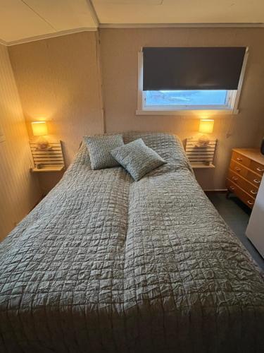 a bedroom with a bed with two pillows and a window at Hos Laura & Valdemar in Nord-Lenangen