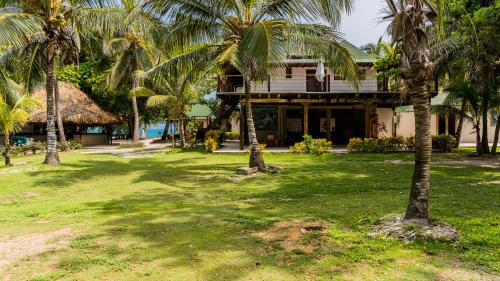 a house with palm trees in front of it at Hotel Rosario de Mar by Tequendama in Isla Grande