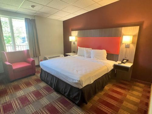 a hotel room with a large bed and a chair at Countryside Suites Kansas City Independence I-70 East Sports Complex Hotel in Independence
