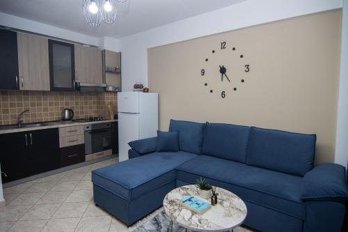 a living room with a blue couch and a clock on the wall at Amazing Paradise Sensation 2 Bedroom Luxury Apartment with a Jacuzzi in Durrës