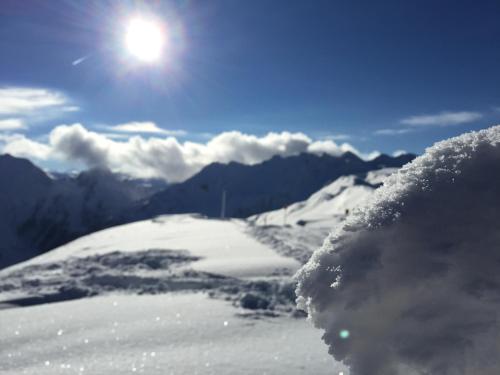 a snow covered mountain with the sun in the sky at Wellnessappartements Margit in Alpbach
