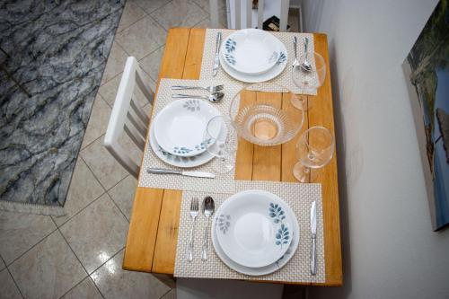 a wooden table with plates and glasses on it at Amazing Paradise Sensation 2 Bedroom Luxury Apartment with a Jacuzzi in Durrës