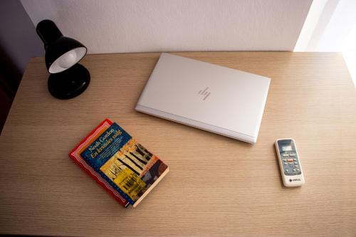 a table with a laptop and a book and a remote control at Amazing Paradise Sensation 2 Bedroom Luxury Apartment with a Jacuzzi in Durrës