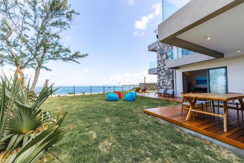 a backyard with a wooden table and a view of the ocean at Ocean Terraces Apt A1 - Your Beachfront Bliss - Brand NEW in Poste Lafayette