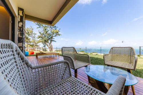 a patio with chairs and a table and the ocean at Ocean Terraces Apt A1 - Your Beachfront Bliss - Brand NEW in Poste Lafayette