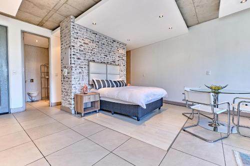 1 dormitorio con cama y pared de ladrillo en Studio Apartment In Melrose Arch en Johannesburgo