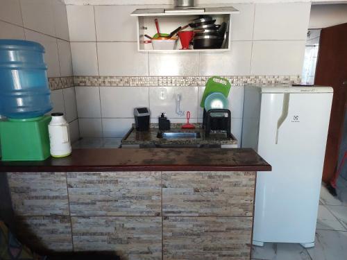 una pequeña cocina con fregadero y nevera. en Linda kitinet, en Cabo Frío